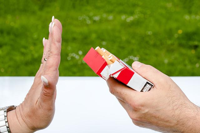 Closeup of hand offering cigarettes, second person holding hand up to refuse