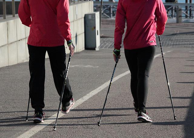 Two people walking on track using Nordic poles