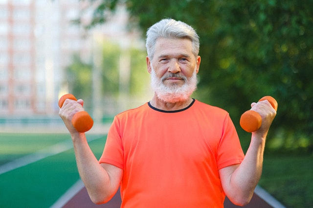 Older man holding small hand weights in curl position