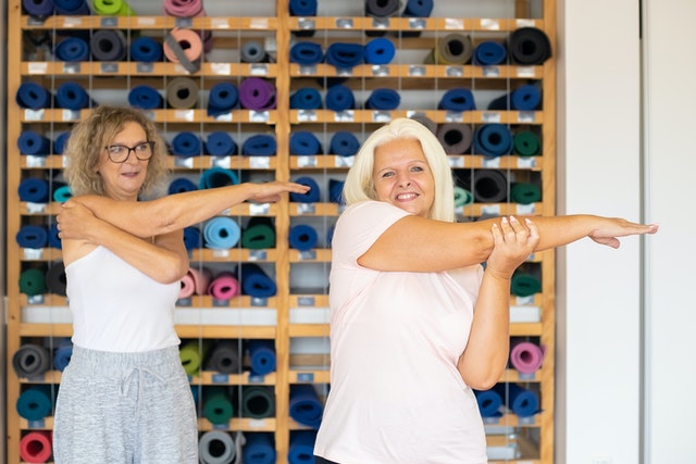 Two women in a yoga studio stretching their upper arms