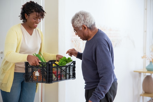 Young woman brining a basket of produce to older man