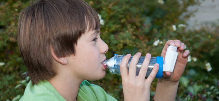 Young boy using an inhaler with a spacer