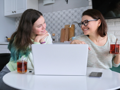 Mother and daughter looking at laptop drinking tea