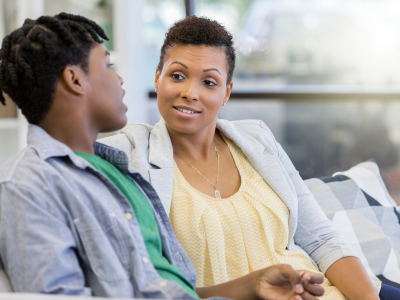 Mother and teen son sitting on couch having discussion