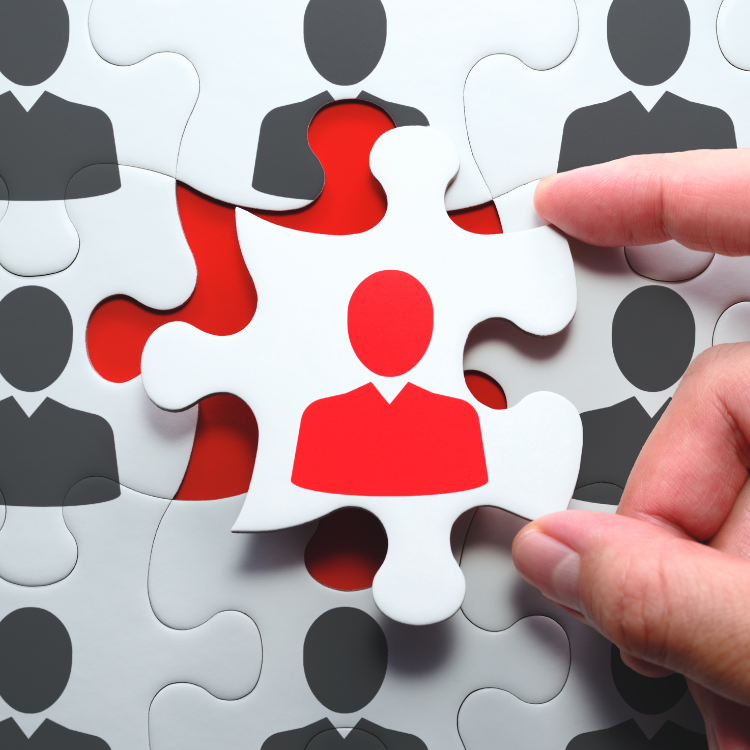 Closeup of person putting puzzle piece in place. Puzzle piece features an icon of a person.